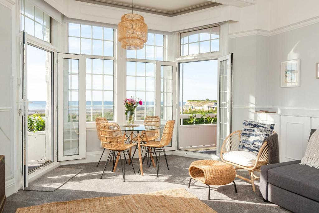 a living room with a table and chairs and windows at SoHot Stays - Sea Views From Every Room in Westgate-on-Sea