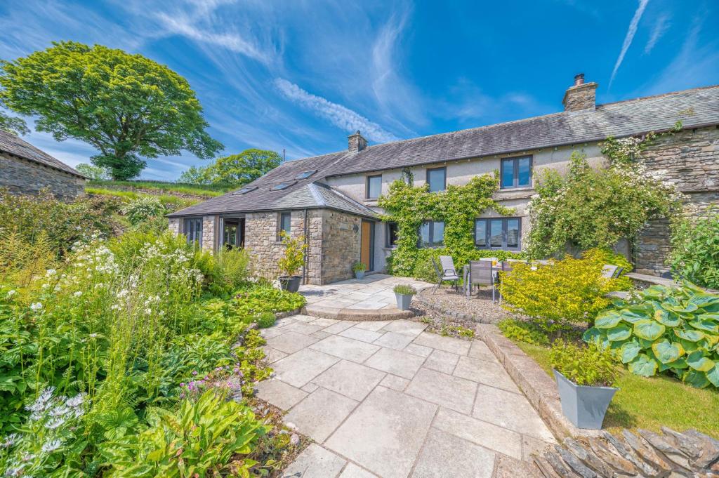 an exterior view of a stone house with a garden at Sandbeds Farmhouse in Kendal