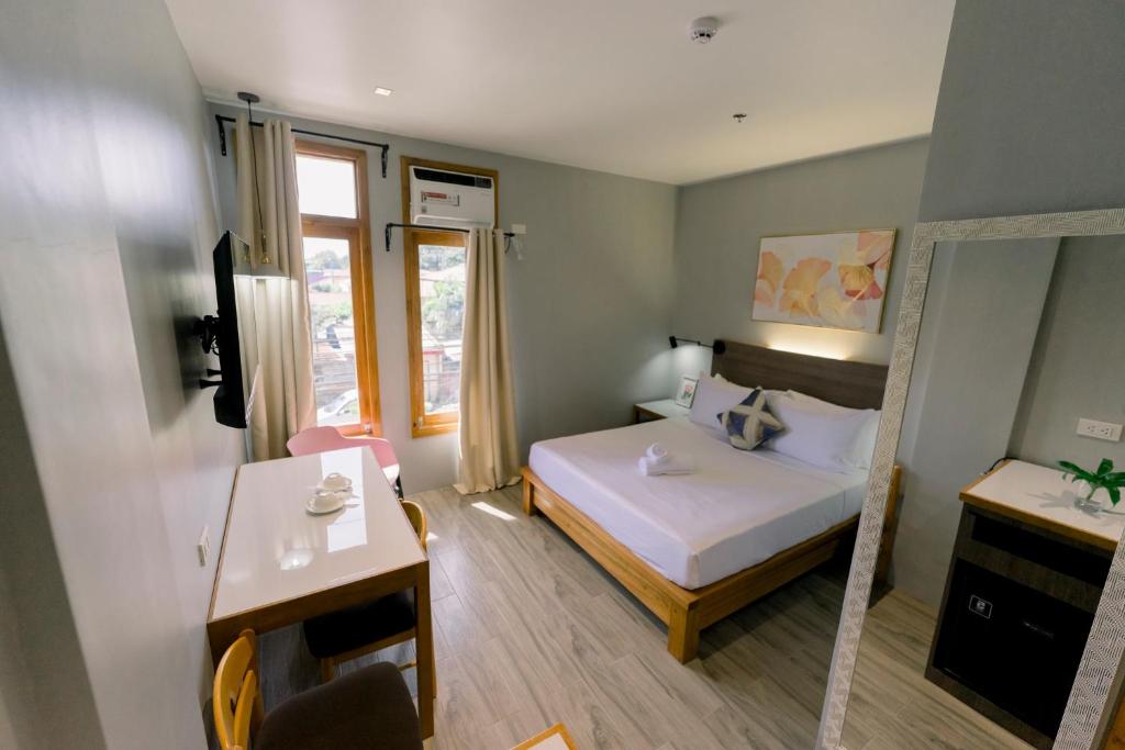 Madonna Hometel and Suites New Pandan في Panabo: غرفة صغيرة بها سرير ومرآة