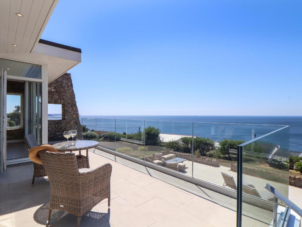 a balcony with a table and chairs and the ocean at Boscregan in Helston