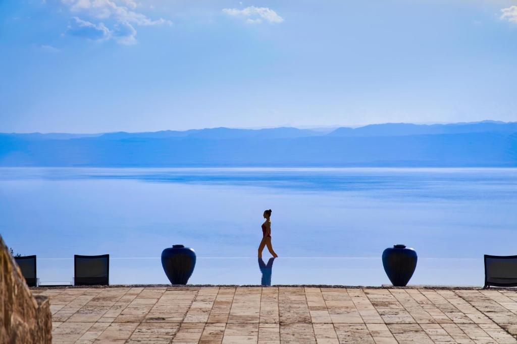 a person standing in front of a body of water at Mövenpick Resort & Spa Dead Sea in Sowayma