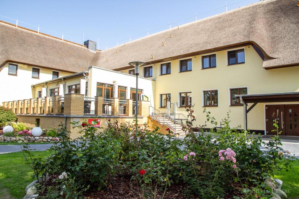 um grande edifício com um alpendre e algumas flores em Ostseehotel Wustrow em Wustrow