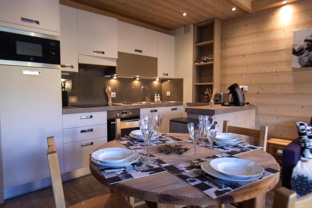 a kitchen with a wooden table with plates and glasses on it at Tignes le Lac - Le Santon bel appartement 4 pers in Tignes