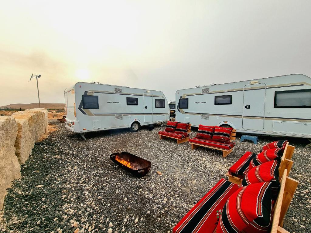 two rvs parked next to chairs and a campfire at Glamping Caravans At The Farm! - גלמפינג קרוואנים בחווה in Mitzpe Ramon