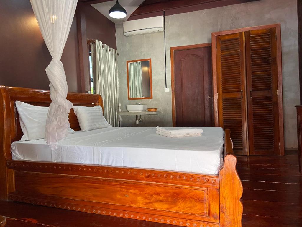 1 dormitorio con cama de madera con sábanas blancas en Sothea Angkor Homestay en Phumi Ta Phul