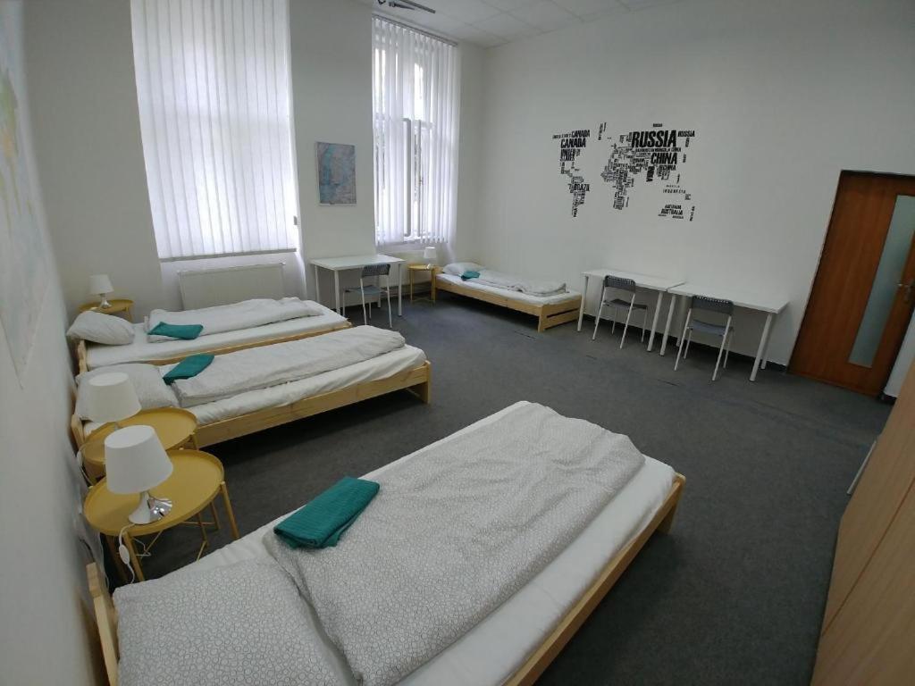a room with three beds and tables and chairs at ApartHostel Brno in Brno