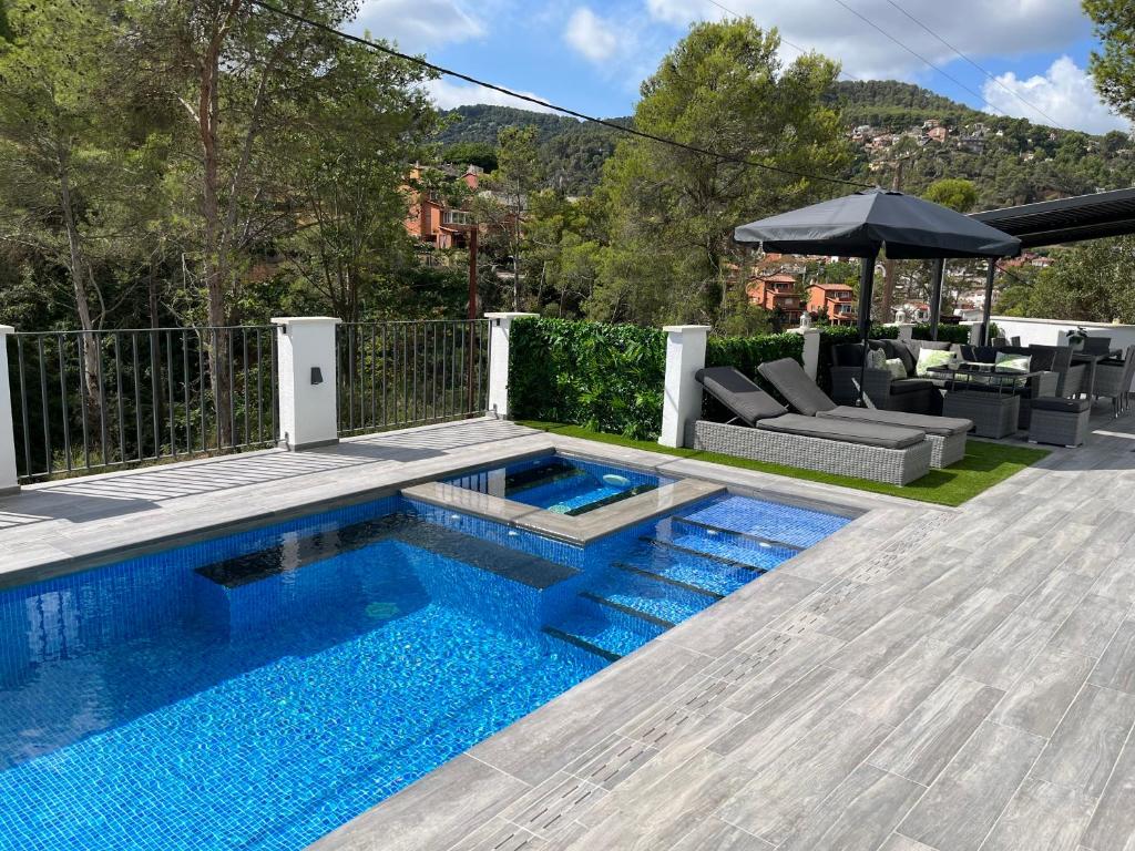 a swimming pool in a backyard with an umbrella at Lux@Spa in Vallirana