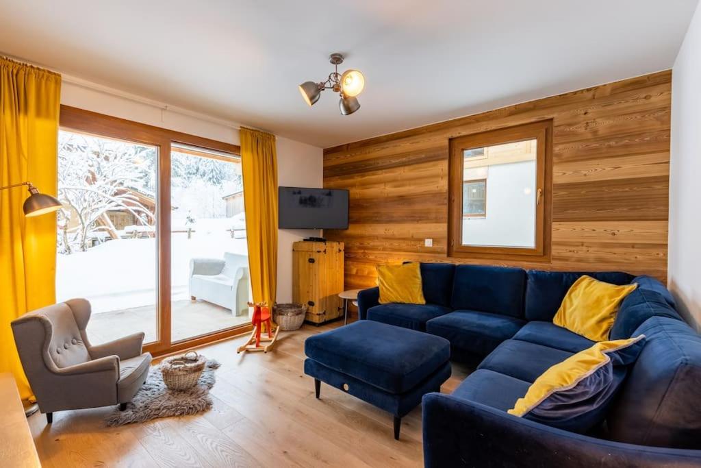 uma sala de estar com um sofá azul e almofadas amarelas em Stylish 2 bed apartment near Les Prodains Gondola em Morzine