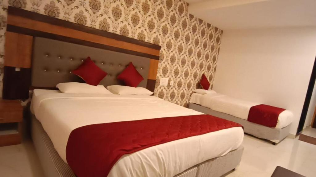 a bedroom with two beds with red pillows at Hotel Woodside Prestige in Tirupati