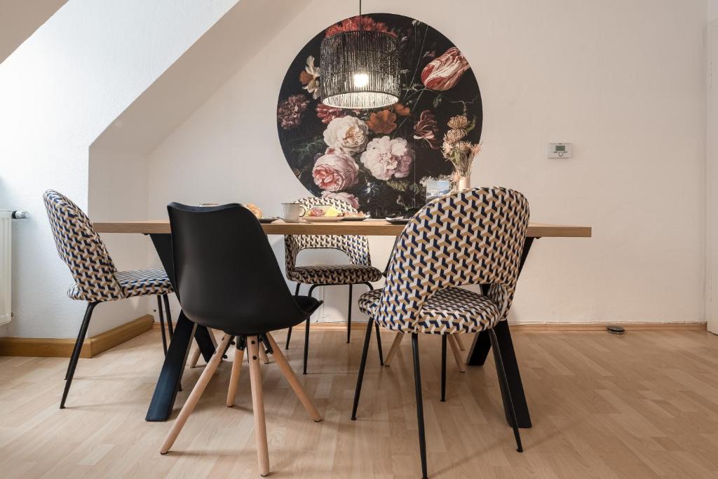 una mesa de comedor con sillas y una pintura en la pared en Altstadt Apartments zentral am Rathaus, en Augsburg