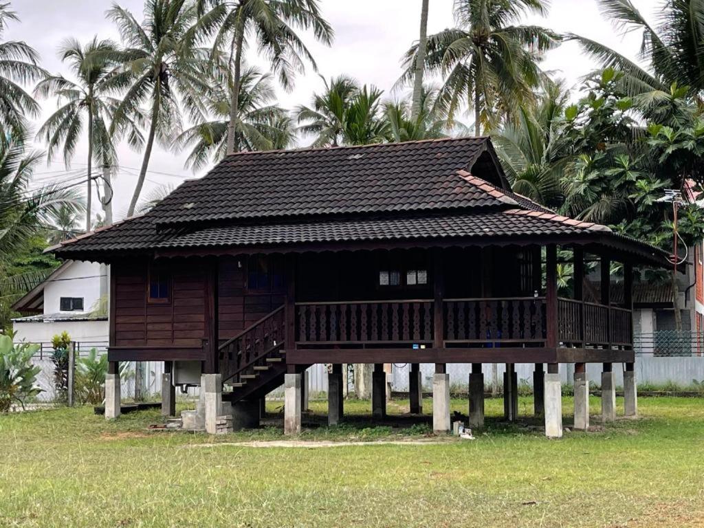 ein Haus auf Stelzen mit Palmen im Hintergrund in der Unterkunft Red Coral Cottage in Tanjung Rhu