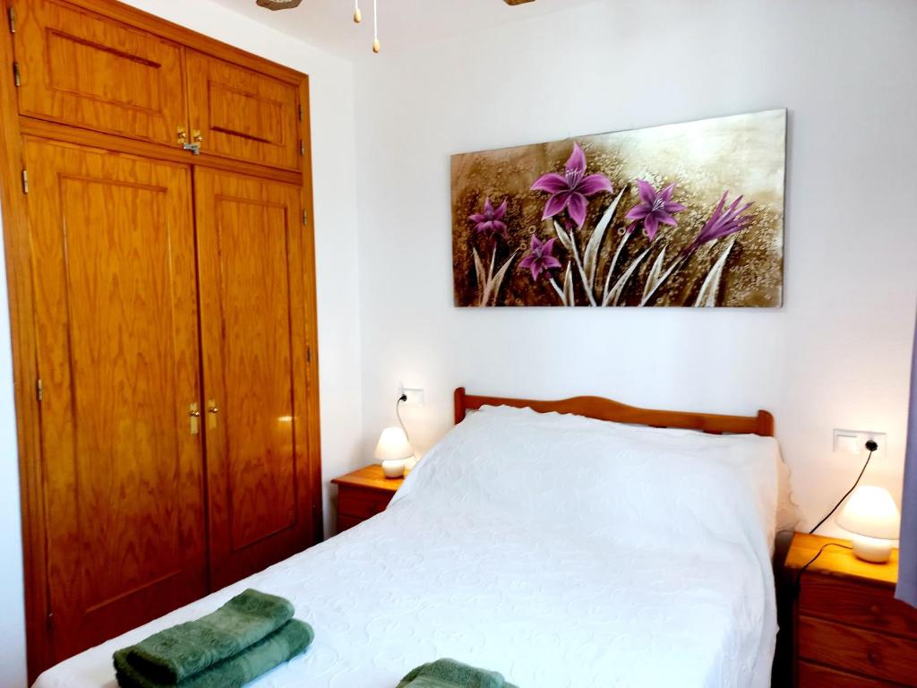 1 dormitorio con 1 cama y una pintura en la pared en Ground Floor Apartment - Opposite pool C, en Playas de Orihuela