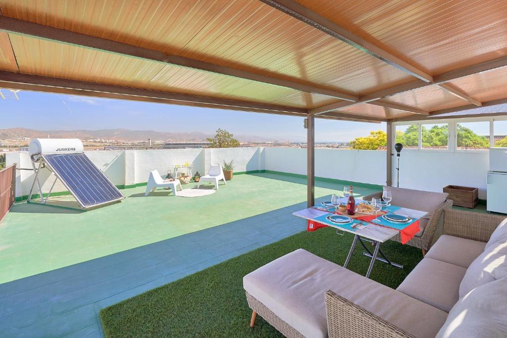 eine Terrasse mit einem Tisch und Stühlen auf dem Dach in der Unterkunft PENTHOUSE NEAR MALAGA TOWN also long term and available car in Málaga