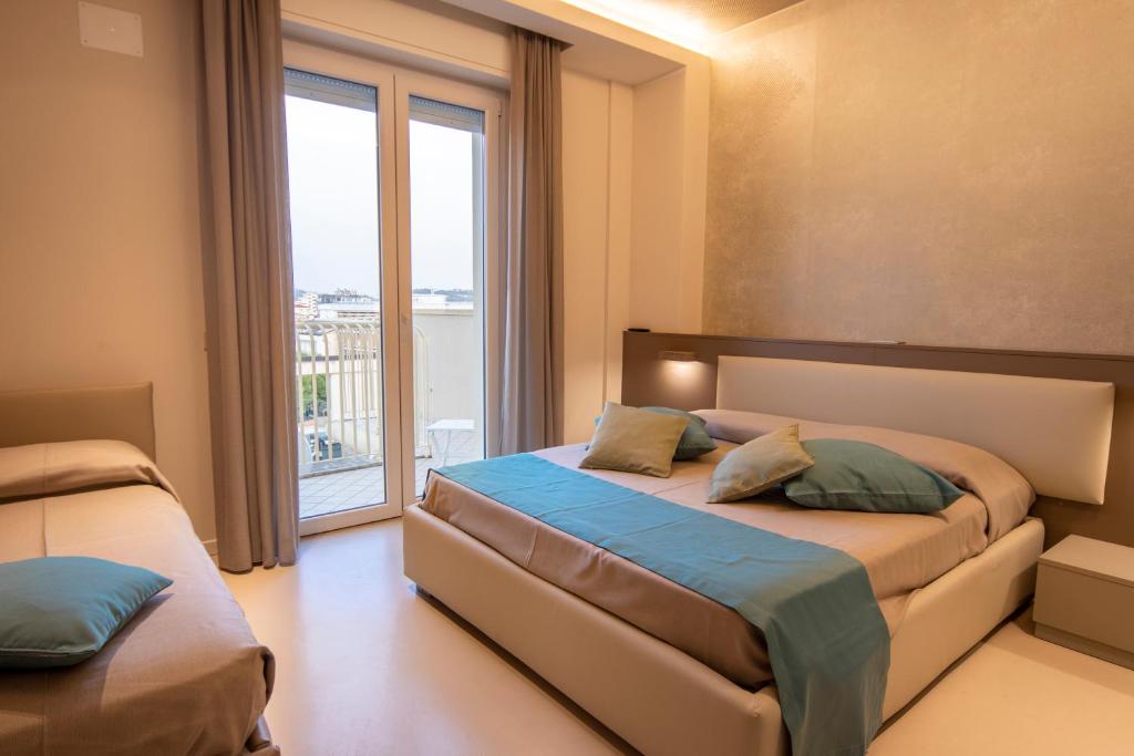 a bedroom with two beds and a large window at Hotel Beaurivage in Cattolica