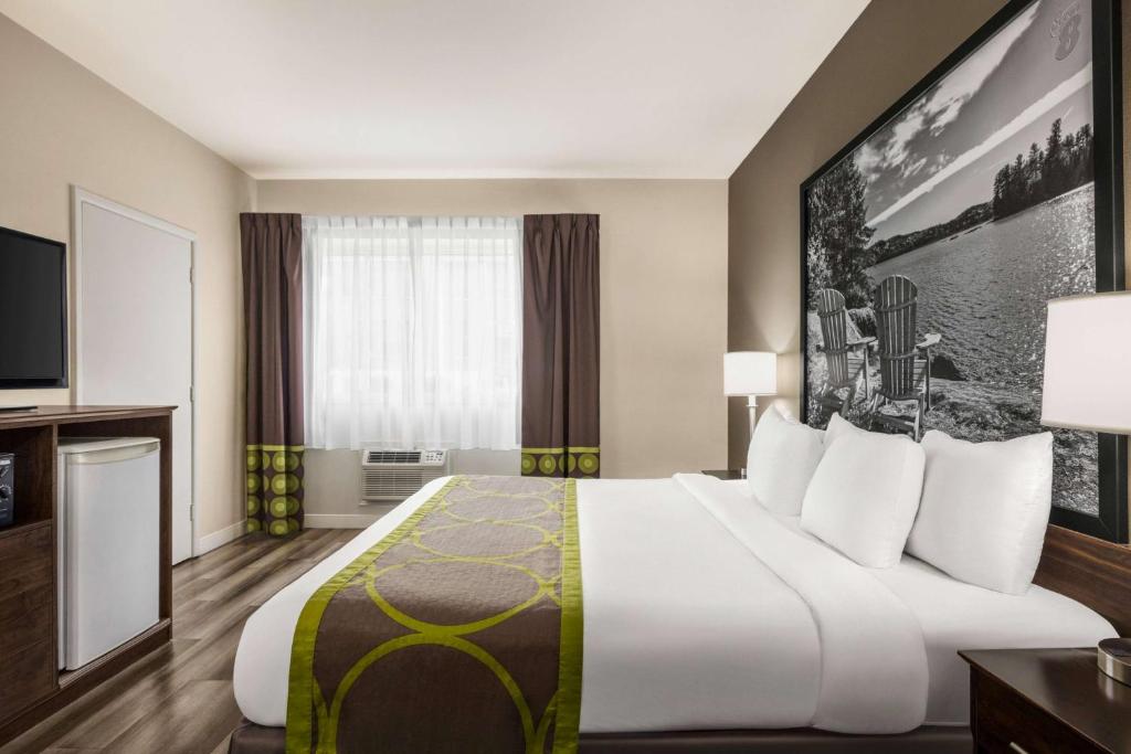 サーニアにあるSuper 8 by Wyndham Sarnia ONの大型ベッドとテレビが備わるホテルルームです。