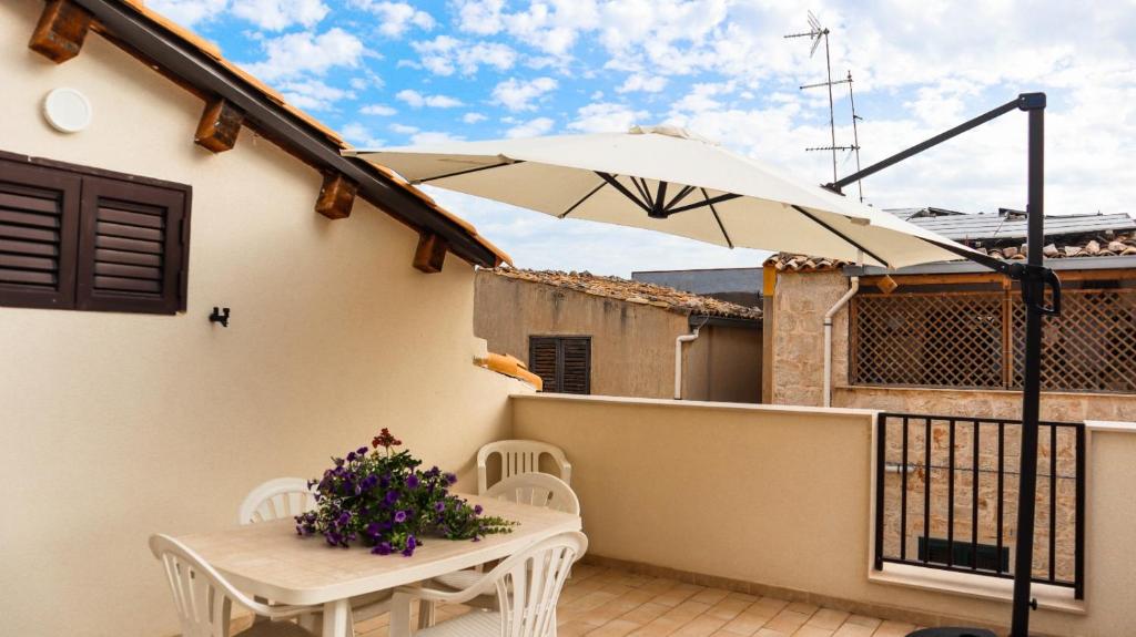 a patio with a table and an umbrella at Le Amiche in Marina di Ragusa