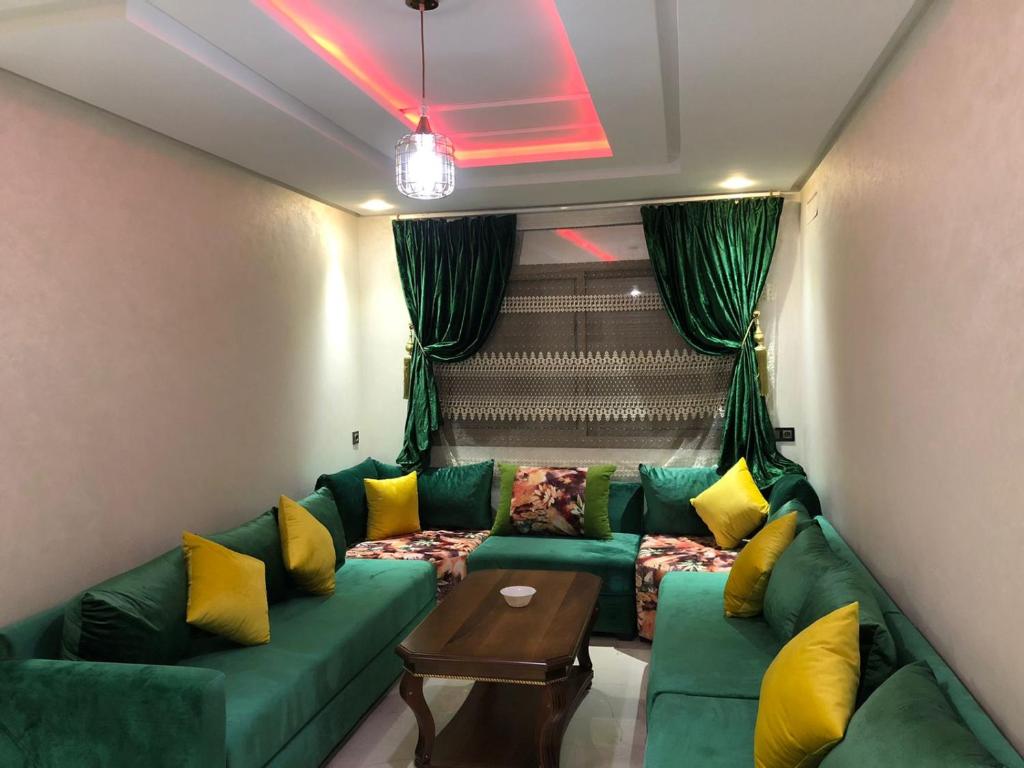 sala de estar con sofá verde y almohadas amarillas en اقامة العائلة en Nador