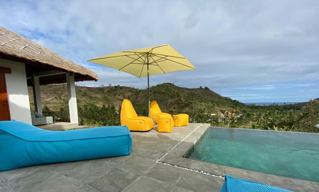 een zwembad met gele stoelen en een parasol bij Lombok Khophilauvillas in Kuta Lombok