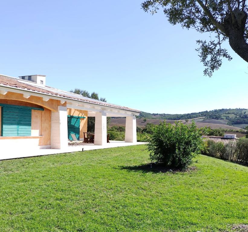 una casa con un césped verde delante de ella en Villa luce e relax en Saturnia