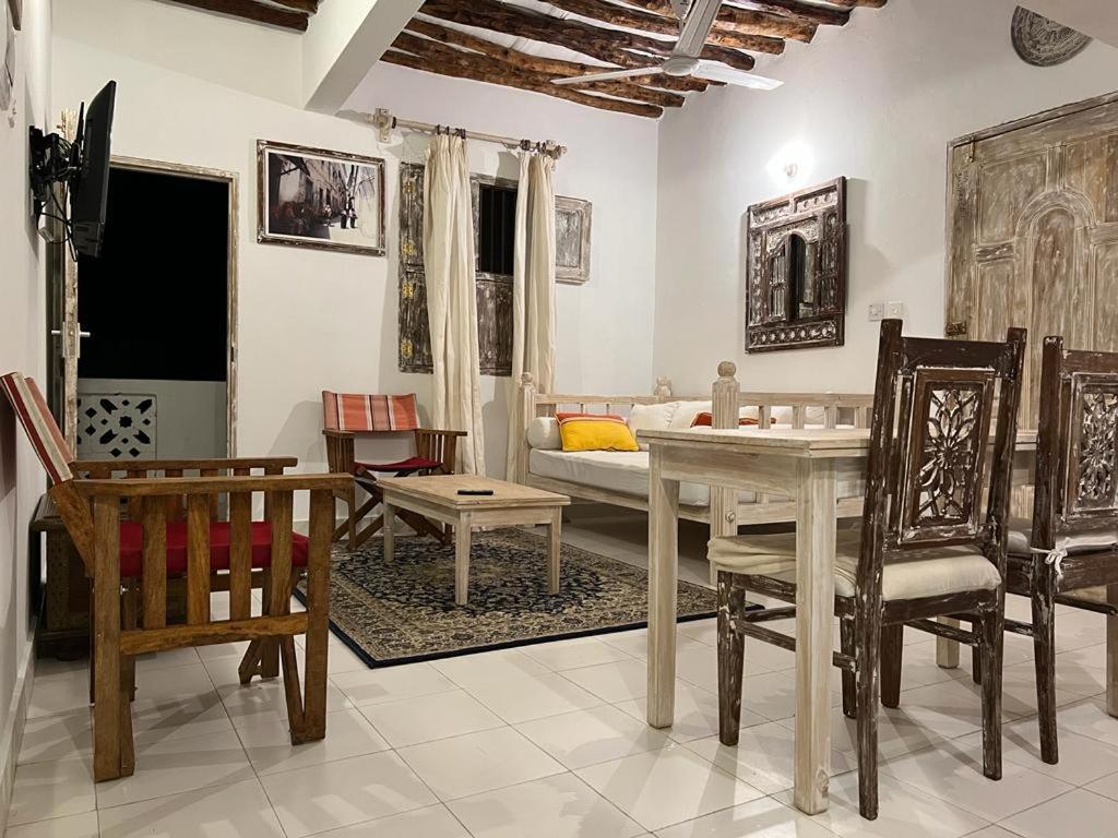 un soggiorno con tavolo, sedie e divano di Beytsalaam Apartments a Lamu