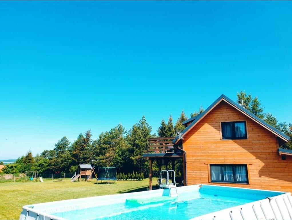 ein Haus mit einem Pool vor einem Haus in der Unterkunft Domek z widokiem na jezioro - Domek Jerzy in Kruklanki