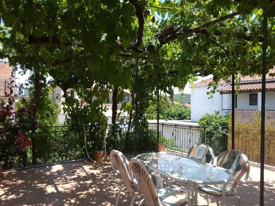 a table and chairs on a patio under a tree at Ευχάριστο σπίτι με ωραίο κήπο in Pylos