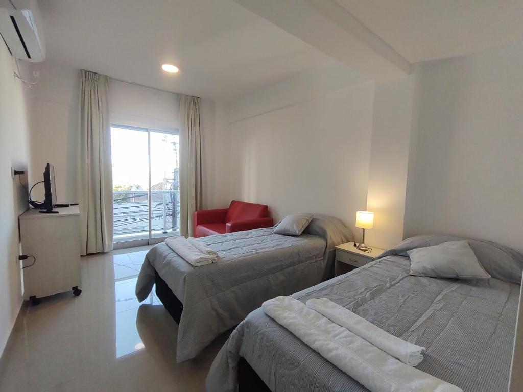 una habitación de hotel con 2 camas y una silla roja en DELFINA suites 2A en La Rioja