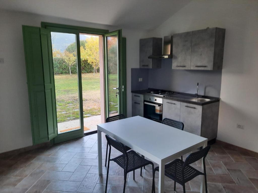 kuchnia z białym stołem, krzesłami i kuchenką w obiekcie Casa Dora w mieście Gubbio