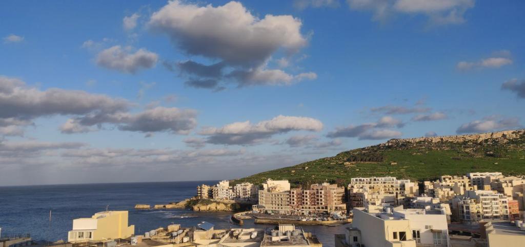 a group of white buildings on a hill next to the ocean at Minute walk to the sea in Żebbuġ