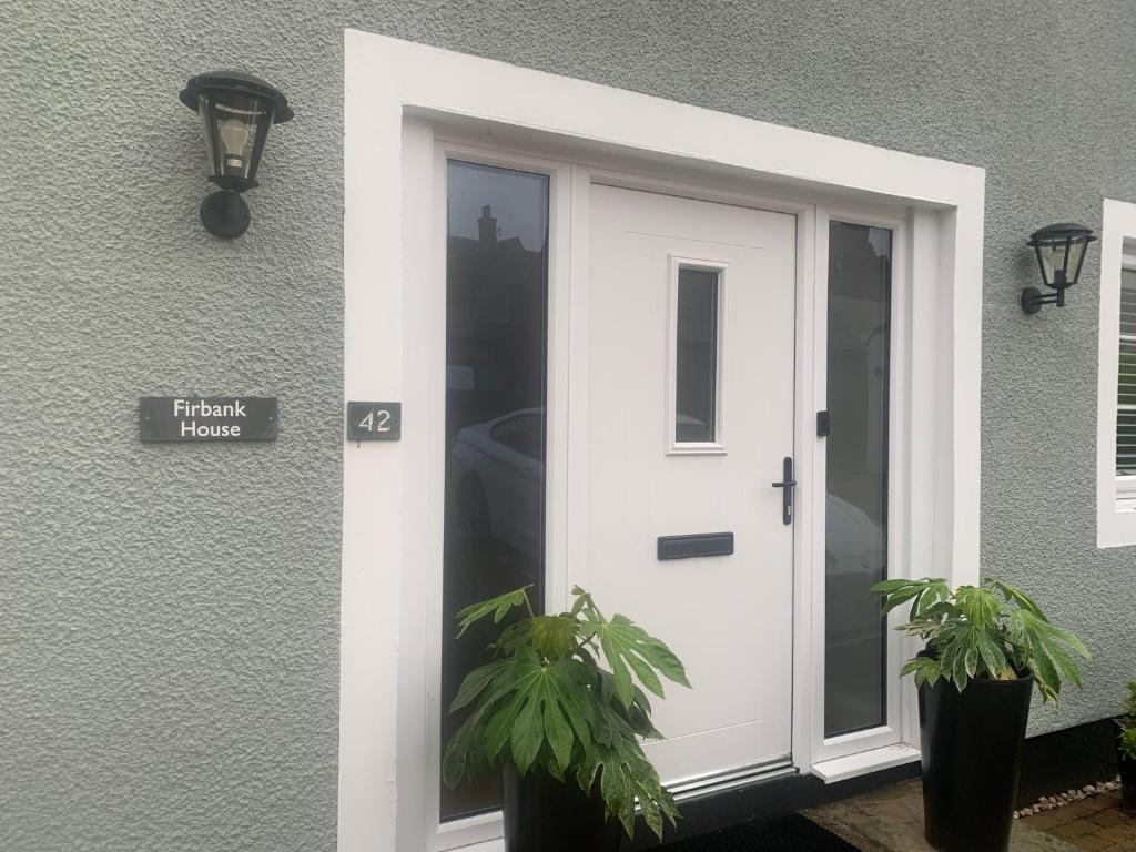 a white door on a house with two plants at Firbank House in Glenrothes