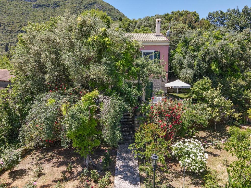 um jardim em frente a uma casa com árvores e flores em Riza Stone Cottage, romantic house, pet friendly em Vátos
