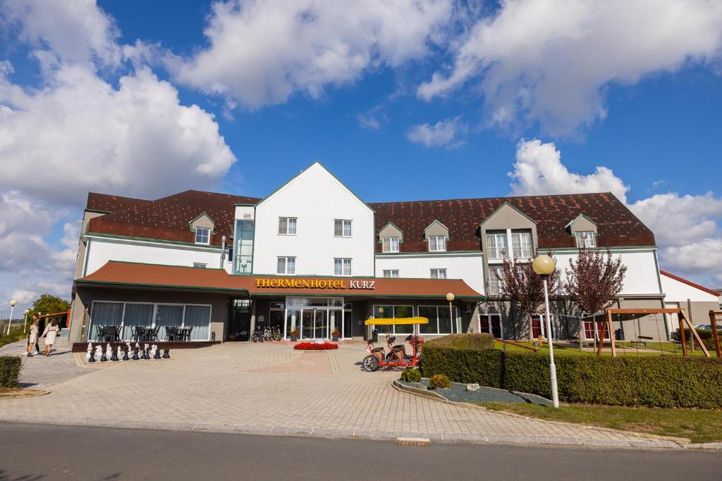 a large white building with a courtyard in front of it at Thermenhotel Kurz in Lutzmannsburg