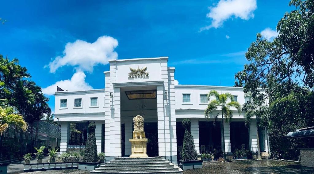 a white building with a statue in front of it at Sundale Hotel in Divulapitiya