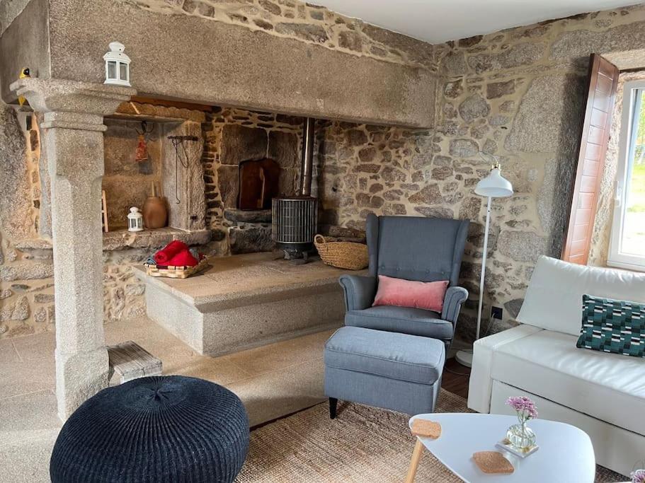 ein Wohnzimmer mit einem Sofa und einem Stuhl in der Unterkunft A Casa do Portal in Campo Lameiro