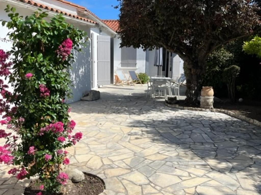 eine Terrasse mit rosa Blumen vor einem Haus in der Unterkunft Maison La Flotte, 5 pièces, 6 personnes - FR-1-544-3 in La Flotte
