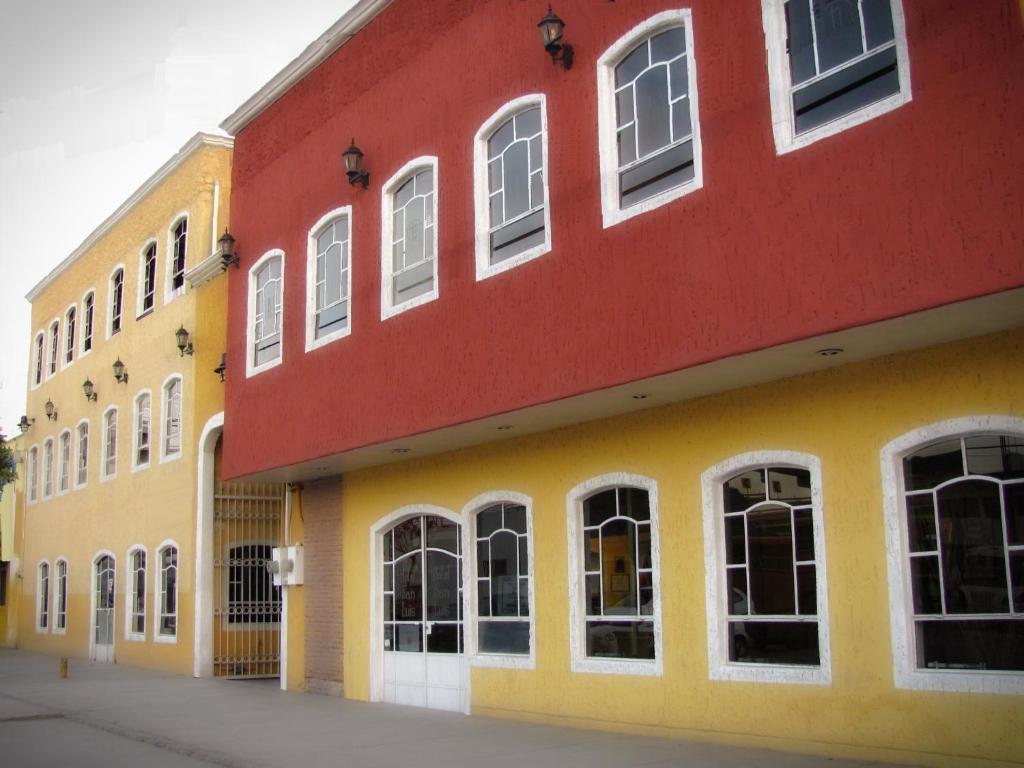 un bâtiment rouge et jaune avec des fenêtres blanches dans l'établissement Hotel San Luis, à San Luis Potosí