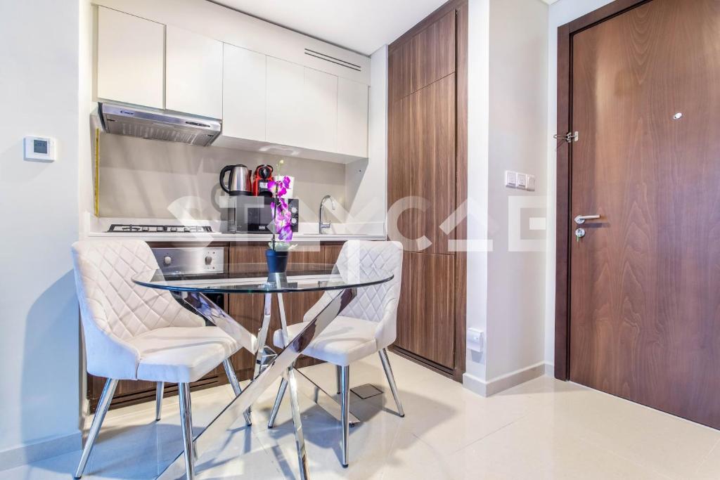 uma cozinha com uma mesa de vidro e 2 cadeiras em Staycae Holiday Homes - Reva no Dubai