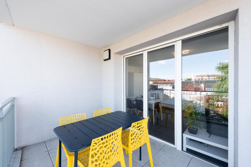 a balcony with a black table and yellow chairs at Bluemary - Spacieux T3 Garage balcon in Lyon