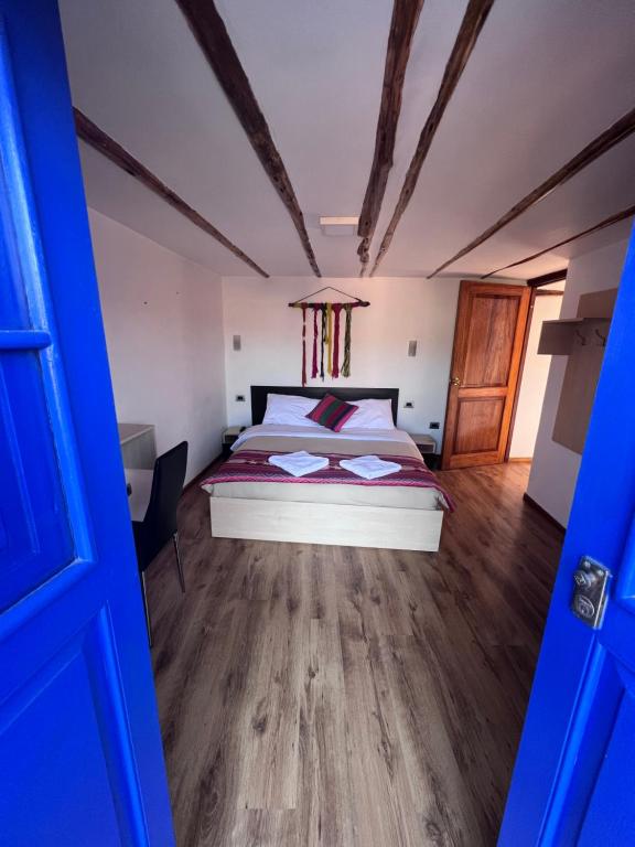 a bedroom with a bed and a wooden floor at Casona les Pleiades in Cusco