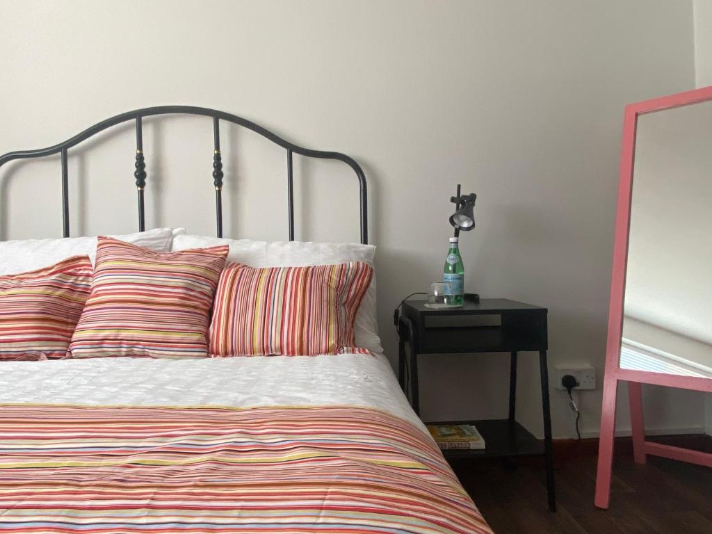 - un lit avec des oreillers rayés et une table avec une lampe dans l'établissement Apple Cottage - Central Frome - Outdoor Space, à Frome