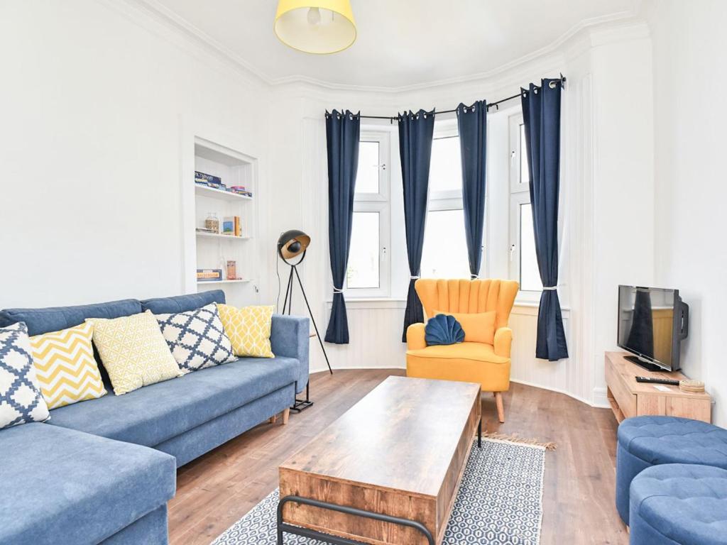 a living room with blue couches and a tv at John Muir Apartment in Helensburgh