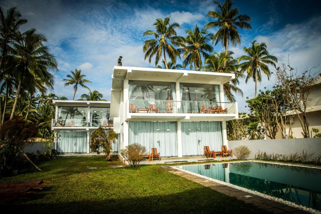 a house with a pool and palm trees at Infinity of Sri Lanka in Paiyagala South
