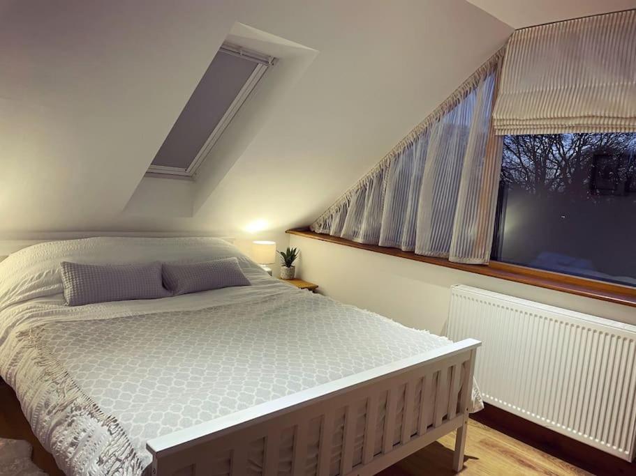 a bedroom with a white bed and a window at The Loft - beautiful countryside apartment in Cullompton