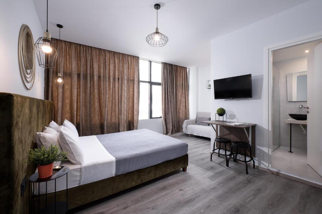 a hotel room with a bed and a desk and a television at Enattica Monastiraki Living in Athens