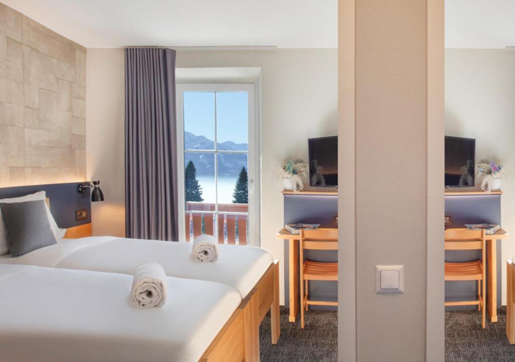 a hotel room with two beds and a window at Villars Lodge in Villars-sur-Ollon