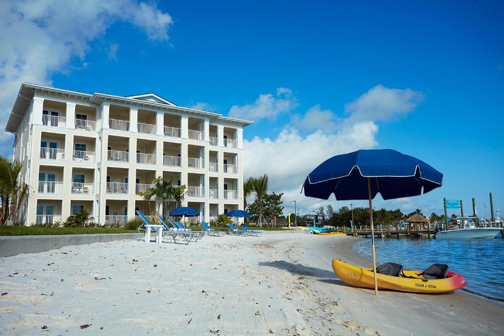 a yellow kayak on a beach with an umbrella and a building at The Pointe Hotel in Jupiter