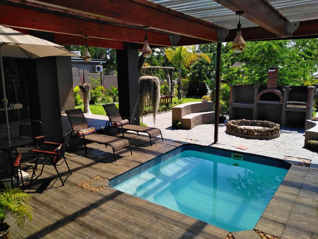 a swimming pool in a yard with chairs and a patio at Villa Pesca Self Catering accommodation in Richards Bay