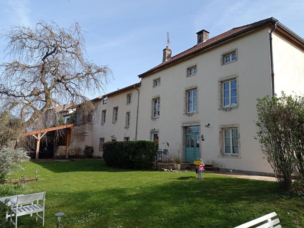 una grande casa bianca con un cortile verde di Chambres d'hôtes La Tuilerie a Blainville-sur-lʼEau