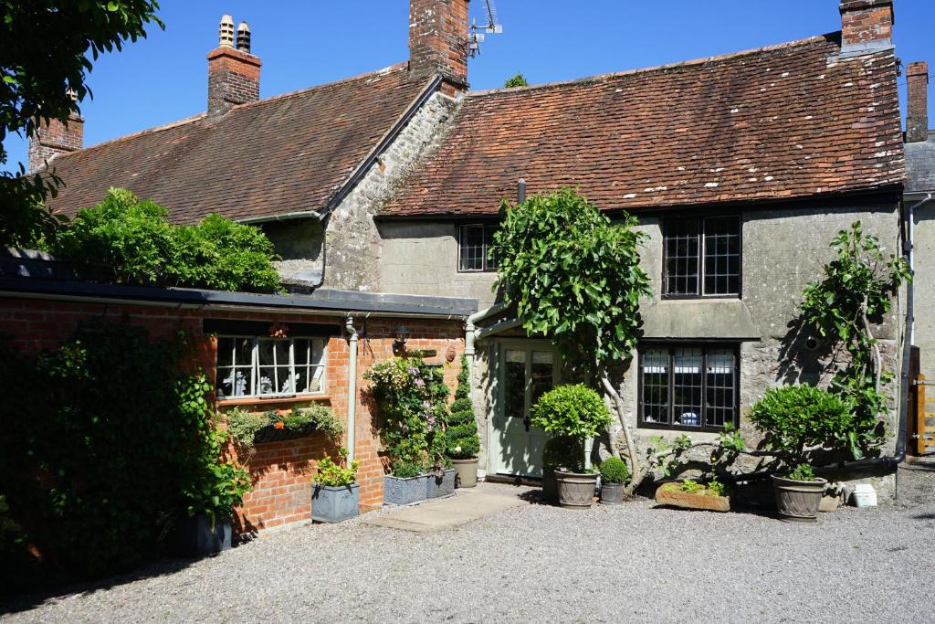 an old brick house with potted plants in front of it at Stunning Historic 2-Bed House in Shaftesbury in Shaftesbury