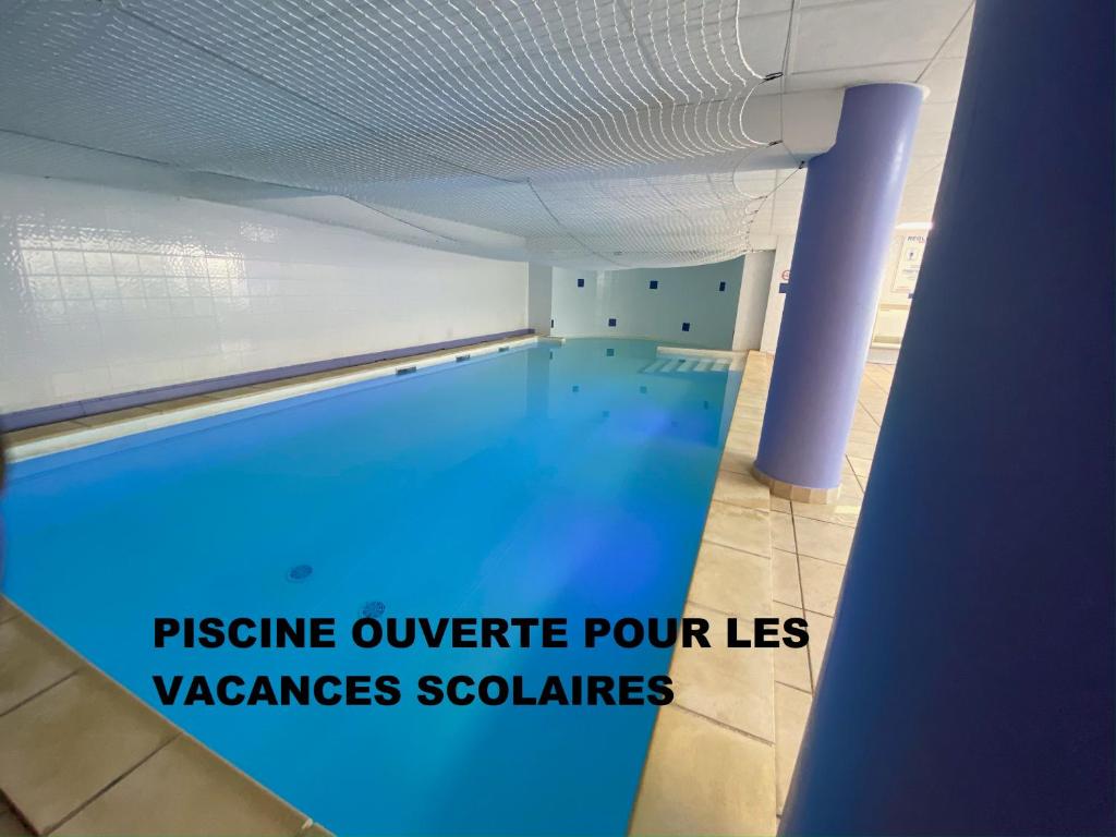 - une piscine d'eau bleue dans un bâtiment dans l'établissement UZES APPART HOTEL Résidence Le Mas des Oliviers, à Uzès